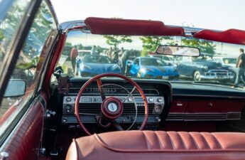 Vintage roadster interior with red leather seats and wood-rimmed steering wheel at a classic car show