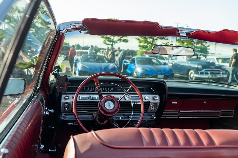 Vintage roadster interior with red leather seats and wood-rimmed steering wheel at a classic car show